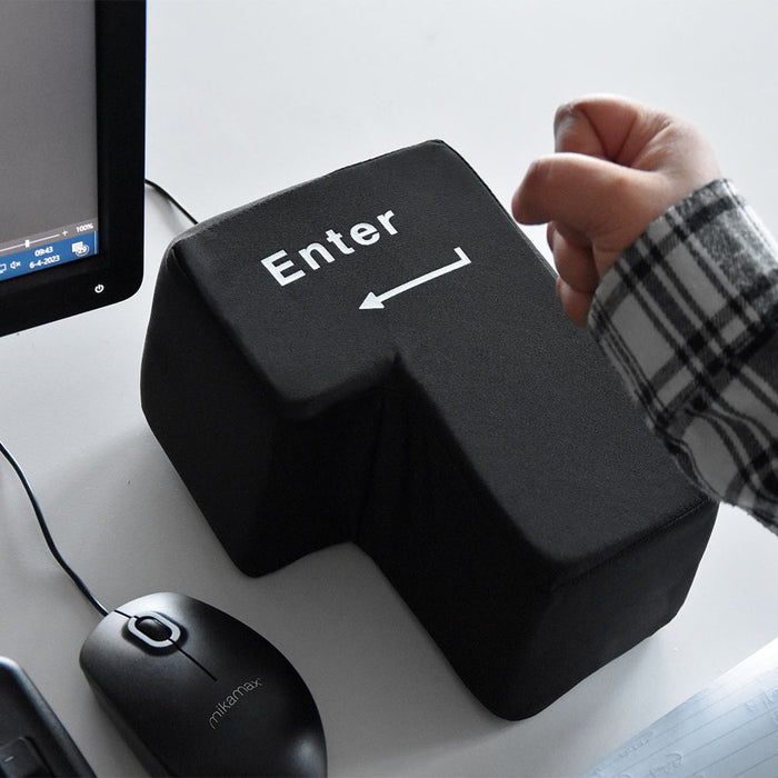 Schwarze, übergroße Enter-Taste mit USB-Kabel auf einem Schreibtisch neben einer Computermaus.